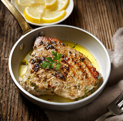 Roasted tuna steak served on a rustic pan on a wooden table