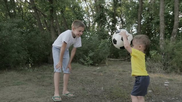 two boys playing with a ball in the park
