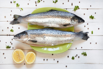 Fresh uncooked salmon on green plate with lemon