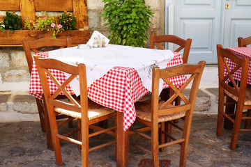 Fototapeta na wymiar Traditional Greek Tavern Table Covered in Red and White Gingham Checkered Tablecloth