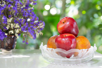 Fruits in the glass basket and vase flower on tile plate