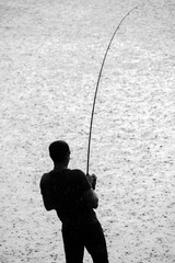Silhouette of Man Fighting Fish in Rain