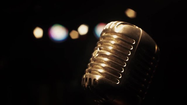 Concert vintage glare microphone on stage in empty retro club under spotlight. Close up.