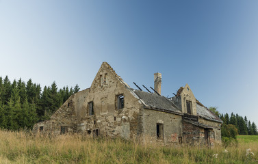 Old ruin of house on meadow after sunset