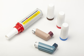 Various asthma inhalers and a peek low meter on white - obrazy, fototapety, plakaty