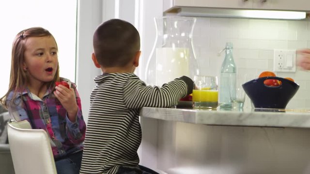 Brother and sister eating fruits and healthy snacks in the kitchen