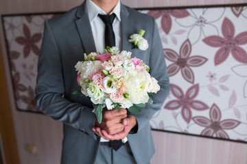 groom holding a wedding bouquet of white roses