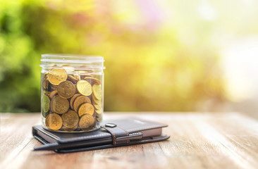 money (coins) in the glass with teddy bear Investment and Interest Concept. Filter soft effect and warm sunset.