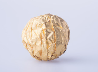 Chocolate ball in a gold foil paper on a background.