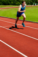 Man running on track at sport stadium.
