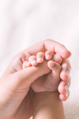 Baby hand holding finger mom on vintage tone. (Selected focus)