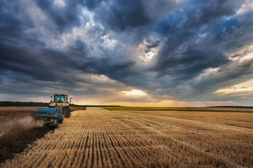 Fototapeta premium Tractor with Plough, Plowing in a Field