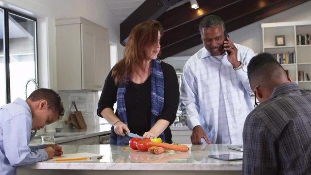 Caucasian mom chopping vegetables with African American family