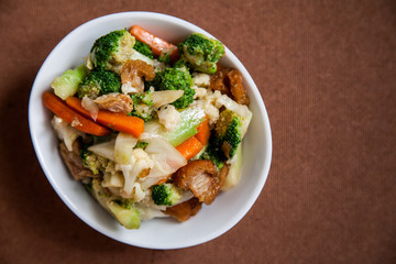 Crispy pork stir-fried with Broccoli and Carrot in Thai style isolated on brown background