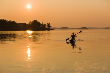 Fototapeta na wymiar Paddle-boarding on lake during sunset