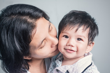 Asian mother kissing her son To show love to each