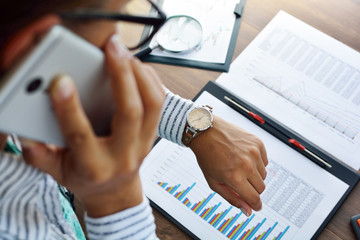 Business analysis - magnifying glass, sheet, graphs (business report) and analyst hand, top view