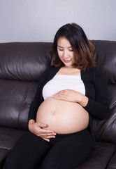 pregnant woman resting at home on sofa