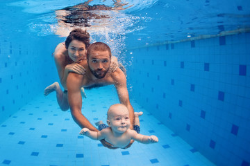 Family fitness - mother, father, baby son learn to swim together, dive underwater with fun in pool Active parent lifestyle, people water sport activity and physical exercises, children swimming lesson