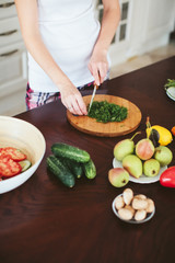 woman in a home clothes prepares vegetarian salad in the kitchen. only hands