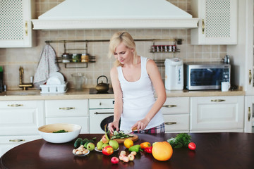 woman in a home clothes prepares vegetarian salad in the kitchen