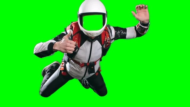 No face template for video editing, slow motion shot of skydiver flying in mid air, with his arms spread and gesturing thumb up looking at camera against green screen background, chroma key