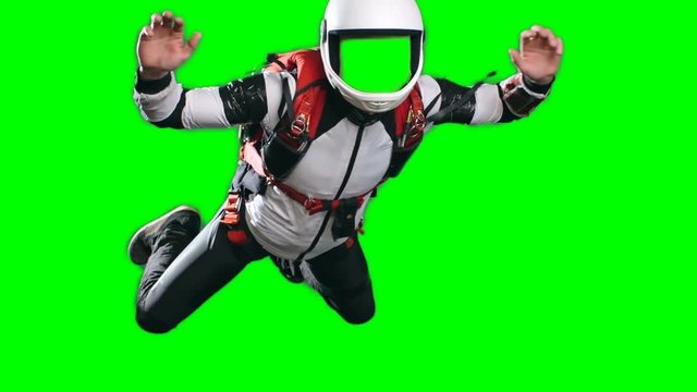 No face chroma key template for video editing, slow-motion shot of young man parachutist in full gear, white helmet, jumpsuit and harness, performing free fall against green screen background