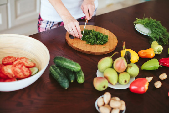 woman in a home clothes prepares vegetarian salad in the kitchen. only hands