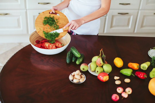 woman in a home clothes prepares vegetarian salad in the kitchen. only hands