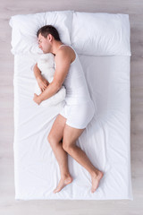 Positive and relaxed young man sleeping on bed