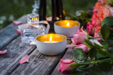 Fototapeta na wymiar Romantic evening. Burning candles, pink roses on a wooden table.
