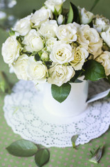 Bouquet of roses in a vase on a wooden table.