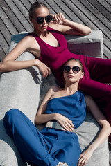 The two girls on the couch. Models in sunglasses relaxing in the sun. - 119321315