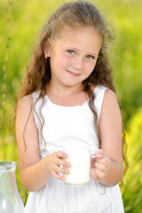 Close up portrait little girl holding glass of milk outdoor summer