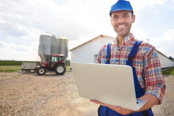 Fototapeta premium Farmer with laptop and his farm.
