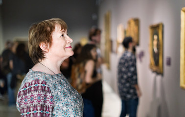 closeup on attentive senior woman visiting museum and enjoying a