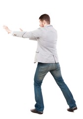 back view of business man pushes wall. guy in a gray jacket waving his arms.