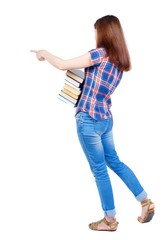 Girl carries a heavy pile of books. back view. Girl in plaid shirt cancer is holding a stack of books and pointing her finger sideways.