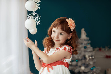 cute little baby in a dress holding a snowflake. The concept of the New Year and Merry Christmas