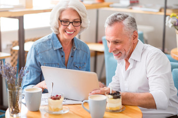 Joyful senior couple using laptop
