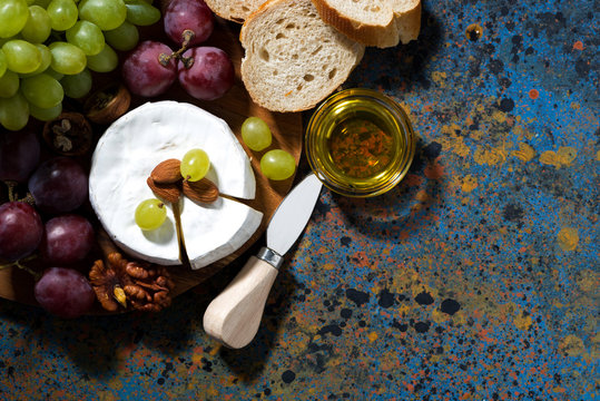 snacks and camembert on dark background, top view