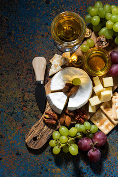 snacks, wine and camembert on a dark background, vertical