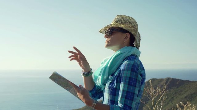 Woman standing on the hill and reading a map, steadycam shot
