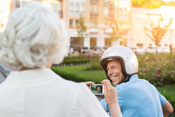 Adult man in helmet smiling. Lady is holding a camera. I'll make some photos. Remember these moments.