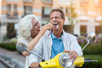 Guy's face in ice cream. Mature couple is laughing. Magic of summer. Look at yourself, sweetie.