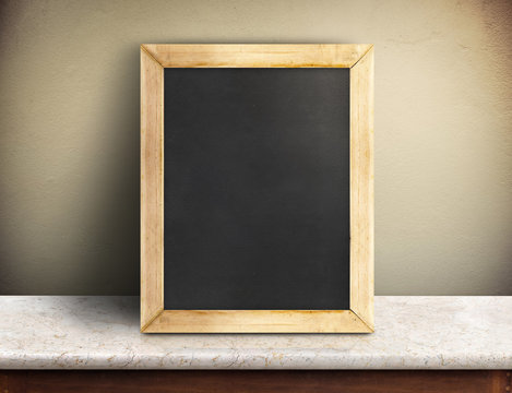 Blank blackboard on marble table at yellow concrete wall,Templat