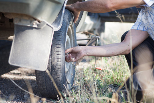 Man repairing punctured wheel in wild forest (focus on hand)