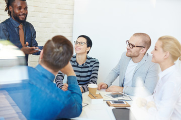 Group of executives at conference table in office listening intently to lively charismatic...
