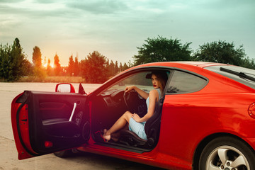 lady with red lips sits in red sport car
