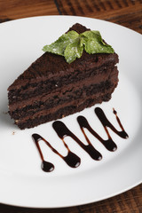 Chocolate cheesecake with mint on a plate. Wooden background.